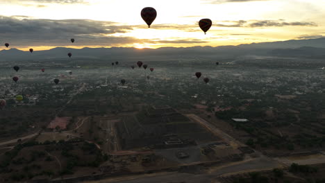 Aerial-view-of-hot-air-balloons-flying-around-the-Pyramid-of-the-sun,-sunrise-in-Teotihuacan,-Mexico