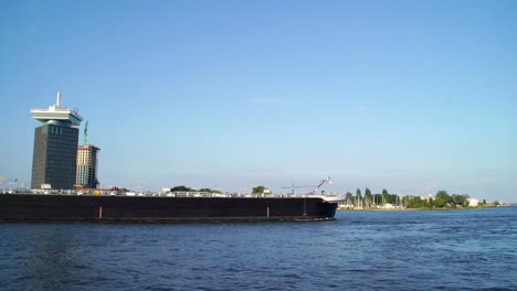 Barcaza-Atravesando-El-Río-Ij-En-Amsterdam,-Países-Bajos---Plano-Amplio