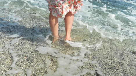 Woman-in-summer-dress-walking-into-Atlantic-ocean-barefoot,-back-view
