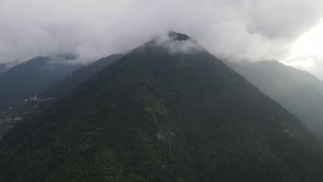 Drone-view-of-mountain-peak-covered-with-clouds,-majestic-mountain-view-on-a-cloudy-day