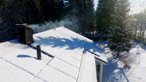 Aerial-view-of-a-smoking-chimney-and-snow-covered-solar-panels-on-a-house-roof