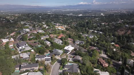 Sweeping-aerial-view-of-a-suburban-neighborhood,-a-wide-panorama-over-trees-and-homes,-with-mountains-in-the-background