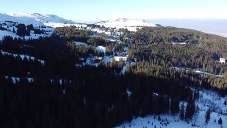 Overhead-aerial-clip-of-Vitosha-ski-resort-near-Sofia,-Bulgaria-with-coniferous-forests-and-snow-covered-peaks-in-the-background