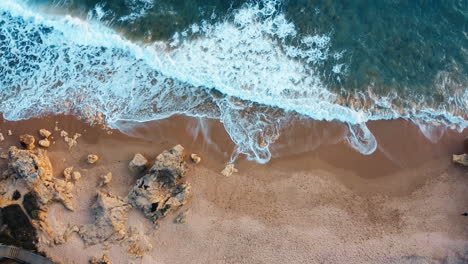 Aerial-top-down-shot-of-rocky-beach-and-ocean,-waves-crashing