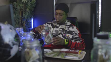 a-black-man-inspects-a-mason-jar-filled-with-marijuana-then-opens-it-to-smell-the-aroma-of-the-pot