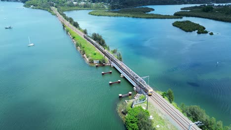 Drone-aerial-train-crossing-over-bridge-railway-tracks-line-Gosford-waterfront-Narara-creek-sea-river-swamp-transport-travel-Central-Coast-Australia