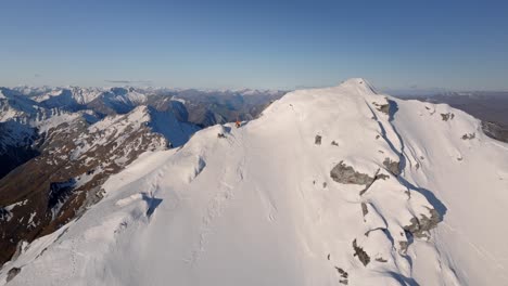 Ein-Kletterer-Steht-Auf-Einem-Schneebedeckten-Berg-In-Der-Wilden-Natur-Mit-Riesigen-Bergen-Und-Riesigen-Tälern-Im-Hintergrund