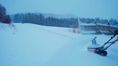 European-Man-Pushing-Snowblower-In-The-Backyard,-Cleaning-Snow-During-Wintertime-In-Norway