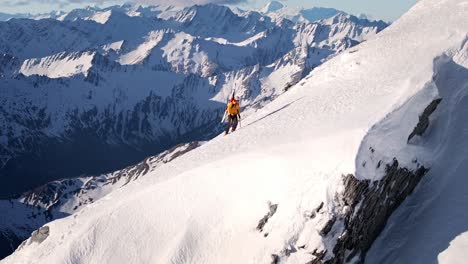 Ein-Mann-Mit-Skiern-Erklimmt-Abgelegene,-Schneebedeckte-Berge-In-Der-Wilden-Natur