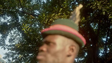 Karamojong-Tribe-Warrior-Wearing-Feather-Hat-In-The-Jungle-At-Sunset-In-Uganda,-Africa