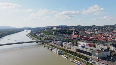 Fly-above-Danube-river-with-aerial-cityscape-view-of-Castle,-SNP-bridge-and-St