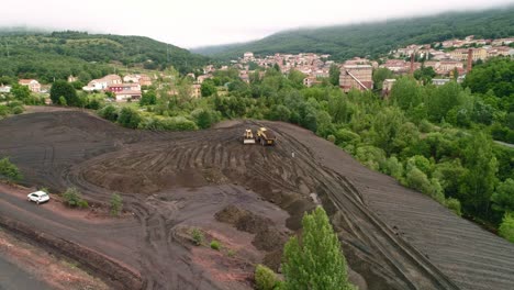 Heavy-truck-unloading-soil-next-to-a-bulldozer,-aerial-view