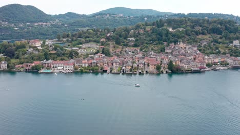 Isola-San-Giulio-on-idyllic-Lake-Orta,-Italy-with-stunning-historic-buildings-before-green-hills