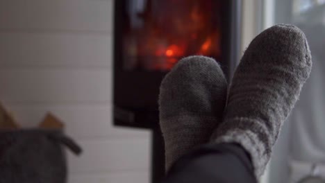 Male-feet-with-knitted-wool-socks-enjoying-a-nice-fireplace-indoors