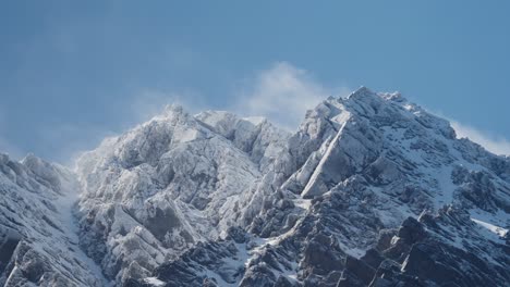 Escarpadas-Montañas-Nevadas-Con-Hermosas-Nubes-Rodando-Con-Un-Gran-Cielo-Azul