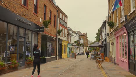 Shot-of-shops-on-both-sides-of-a-road-in-quaint-street,-Twickenham-district-in-London,-England-on-a-cloudy-day
