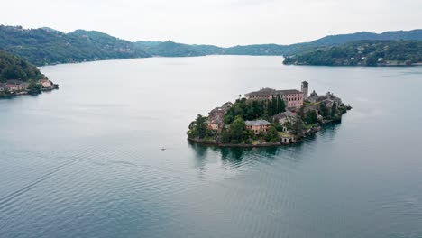 Isola-San-Giulio-on-Lake-Orta-in-Italy,-serene-waters-with-lush-greenery,-aerial-view