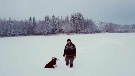 Hombre-Y-Su-Perro-Mascota-Malamute-De-Alaska-En-Nieve-Profunda---Plano-Amplio