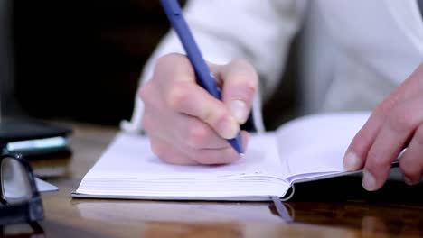 woman-writing-notes-with-a-pen-at-a-office-table-holding-payment-credit-card-with-people-stock-video-stock-footage