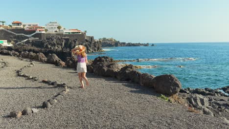 Caucasian-girl-in-summer-clothes-running-slowmo-on-pebbles-beach-along-coast