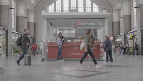 Belebte-Bahnhofsszene-Mit-Reisenden-Und-Einem-DB-Informationsschalter,-Die-Ein-Gefühl-Für-Das-Tägliche-Pendeln-Und-Den-öffentlichen-Nahverkehr-Vermittelt