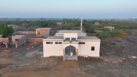Dawn-over-a-house-in-Nawabshah-village,-Sindh---aerial