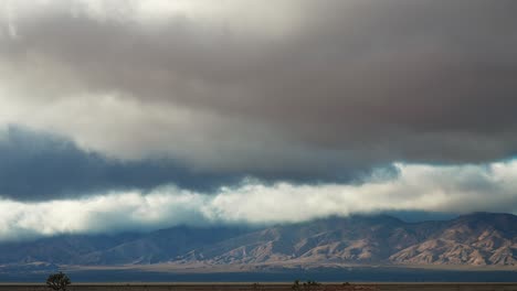 Dramatic-sky-over-mountain-range-with-desert-land-in-the-foreground,-timelapse