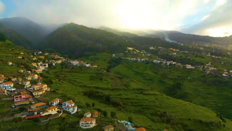 Aerial-view-showing-village-on-green-mountains-of-Madeira-Island-during-sunset-time---Beautiful-scenery-in-tropical-landscape-of-Portugal