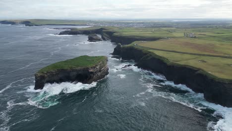 Aerial-drone-view-over-waves-breaking-along-Kilkee-cliffs,-County-Clare-in-Ireland