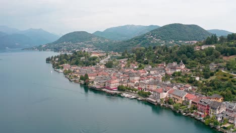 Isola-di-San-Giulio-on-Lake-Orta,-Italy,-showing-the-lush-landscape-and-quaint-buildings-near-the-water,-aerial-view