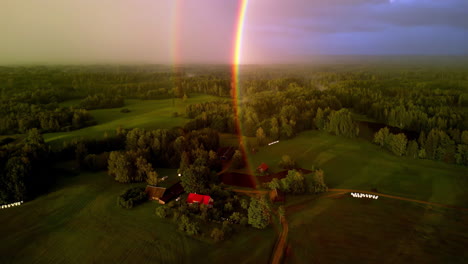 Drone-shot-of-a-storm-brewing-over-rural-farmland-with-a-double-rainbow