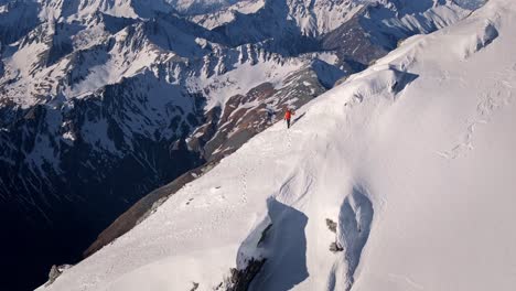 A-man-with-skis-climbs-remote-Snowy-Mountains-in-the-wild-reaches-of-nature