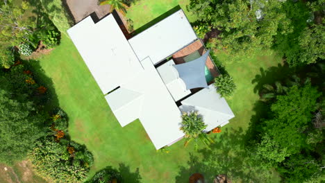 Rotating-drone-shot-of-a-large-rural-home-with-a-swimming-pool,-manicured-lawns-and-large-shed