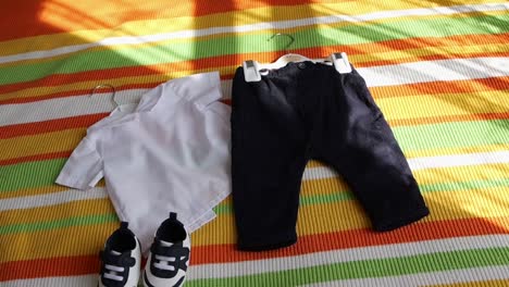 Bunt-Gestreifter-Hintergrund-Mit-Ausgelegter-Babykleidung-Und-Schuhen,-Perfekt-Für-Familien-,-Eltern--Und-Einzelhandelsthemen