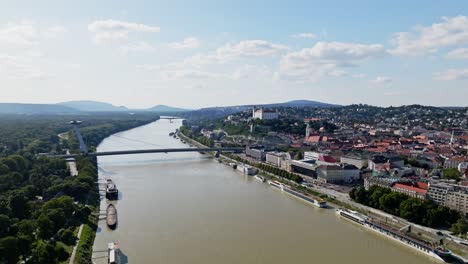 Fly-above-Danube-river-with-aerial-view-of-Castle,-SNP-bridge-and-St