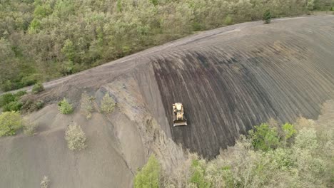 Bulldozer-working-on-a-steep-slope,-aerial-view