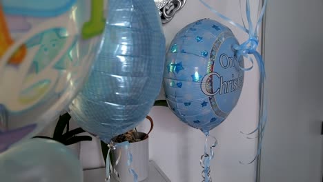 Static-shot-of-sparkly-blue-christening-balloons-with-silver-text-and-curling-ribbons-for-a-special-celebration