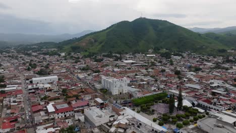 Drone-panoramic-shot-of-Tecalitlan,-Jalisco-with-cathedral-and-tropical-mountains-in-background,-Mexico---Establishing-drone-flight