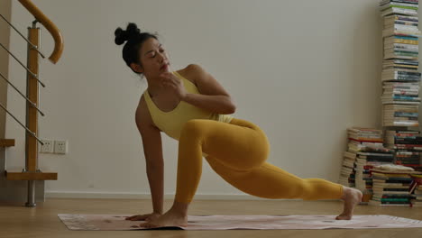 Asiatic-woman-practicing-yoga-asana-exercises-at-home-wearing-yellow-sportswear-in-modern-apartment-room,-daily-workout-healthy-habits-routine