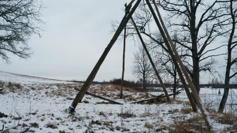 Swing-constructed-from-wood-move-by-itself,-snowy-winter-and-overcast-day