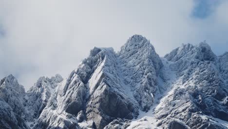 Schroffe-Schneebedeckte-Berge-Mit-Wunderschönen-Wolken,-Die-Vor-Einem-Blauen-Himmel-Auftauchen