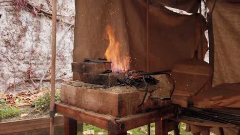 Close-shot-of-blowers-stoking-a-brick-forge-fire,-rural-Fabric-cabin,-Blow-Ashes