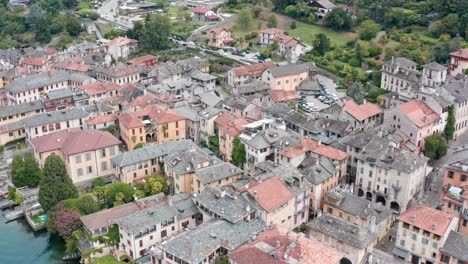 Isola-San-Giulio-on-Lake-Orta-in-Italy,-showing-beautiful-historical-buildings-and-lush-gardens-and-trees,-aerial-view