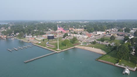 National-flag-of-USA-waving-in-township-of-New-Baltimore,-aerial-drone-view