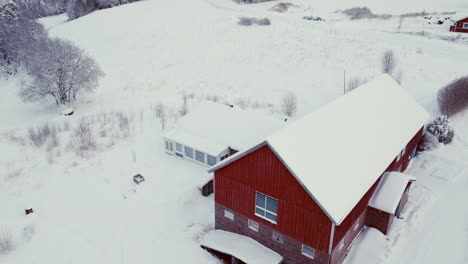 Snowy-Cabin-And-Forest-During-Wintertime---Aerial-Shot