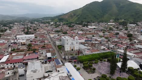Aerial-establishing-shot-of-Mexican-City-named-Tecalitlan,-Jalisco,-with-mountain-range-during-cloudy-day---rising-shot