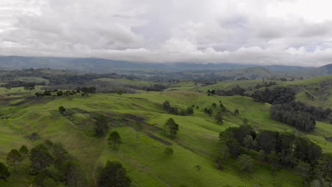 Reverse-aerial-shot-of-rolling-green-hills-of-Eastern-Highlands-province,-Papua-New-Guinea