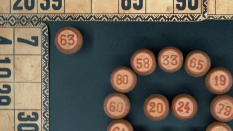 Cinematic-close-up-smooth-rotating-zoom-out-shot-from-above-of-a-Bingo-wooden-barrels-in-a-circle,-woody-figures,-old-numbers-background,-vintage-board-game,-professional-lighting,-slow-motion-4K
