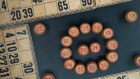 A-creative-close-up-smooth-zoom-out-rotating-shot-from-above-of-a-Bingo-wooden-barrels-in-a-circle,-woody-figures,-old-numbers-background,-vintage-board-game,-professional-lighting,-slowmotion-120-fps