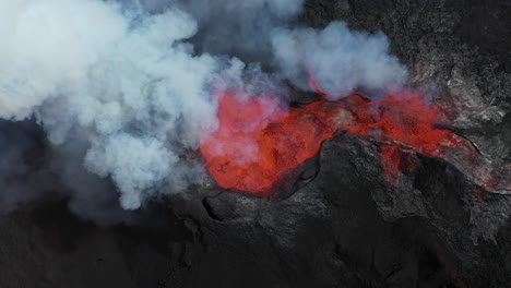 Aerial-from-the-top-shot-of-an-active-volcano-with-flowing-magma-releasing-hot-gases,-fumes-and-smoke